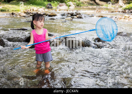 Cinese asiatici bambina la cattura del pesce con rete da pesca nel torrente. Foto Stock