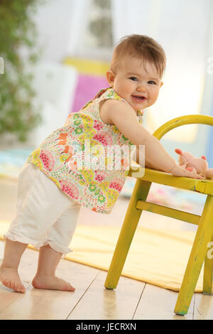 Baby, 10 mesi, alzarsi, tenere premuto sulla sedia, estate, Foto Stock