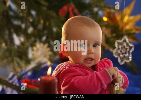 Baby, 6 mesi, sedersi, albero di Natale, skyer, presenta grandi occhi, Foto Stock