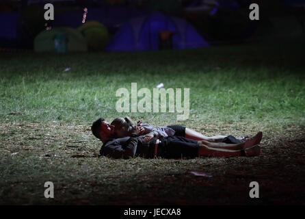 Un giovane che abbraccia sull'erba nelle prime ore del mattino presso il festival di Glastonbury, presso l'azienda agricola degna in Pilton, Somerset. Stampa foto di associazione. Picture Data: Venerdì 23 Giugno, 2017. Vedere PA storia SHOWBIZ Glastonbury. Foto di credito dovrebbe leggere: Yui Mok/PA FILO Foto Stock