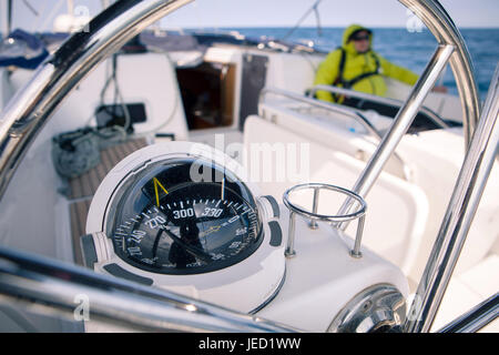 Chiusura del compasso nautico su yacht, sullo sfondo di un marinaio Foto Stock