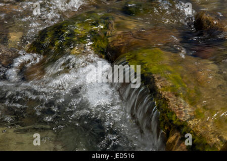 L'acqua che scorre su grossi massi in Langstrath Beck Cumbria Foto Stock