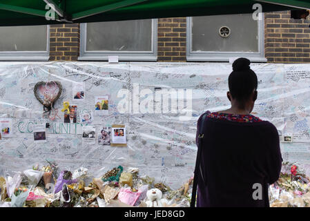 Londra, Regno Unito. Il 23 giugno, 2017. Una donna viste omaggi floreali e messaggi in corrispondenza di uno dei tanti monumenti commemorativi delle vittime. Nove giorni su, la polizia hanno riferito che la torre Grenfell incendio nella zona ovest di Londra ha iniziato in un frigo-congelatore, e al di fuori di rivestimento e isolamento fallito i test di sicurezza. Credito: Stephen Chung/Alamy Live News Foto Stock