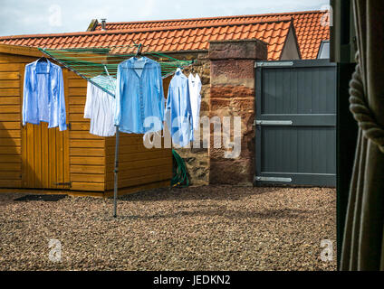 Vista attraverso la finestra di lavaggio appesi ad asciugare all'aperto su essiccatore rotante nel cortile giardino, cancello in legno e Tettoia da giardino, East Lothian, Scozia, Regno Unito Foto Stock