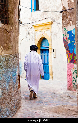 Berber uomo in abito tradizionale a piedi nella medina grafitti wallled vicoli Foto Stock