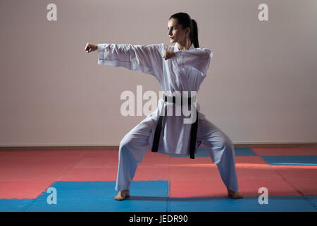 Giovane donna di mettere in pratica il suo Karate si muove - Bianco Kimono - Cintura nera Foto Stock