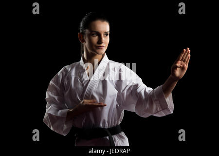 Giovane donna musulmana in kimono tradizionali di mettere in pratica il suo Karate si muove - Isolato su sfondo nero Foto Stock