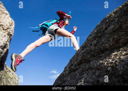 Spagna, Madrid, giovane donna il salto tra rocce durante una giornata di trekking Foto Stock