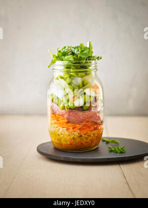 La conservazione di un vasetto di frumento con insalata di verdure, uova sode e fette di manzo Foto Stock
