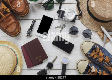 Vista superiore per uomo e donna di accessori al concetto di viaggio.Il bianco e il nero cellulare,aereo,hat,passaporto,guardare,occhiali da sole,scarpe e tasto sulla tavola di legno. Foto Stock