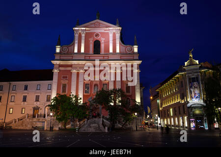 La facciata rosa della chiesa francescana di annunciazione accanto alla casa Urbanc Luxury department store al crepuscolo Preseren Square Ljubljana Slovenia Foto Stock