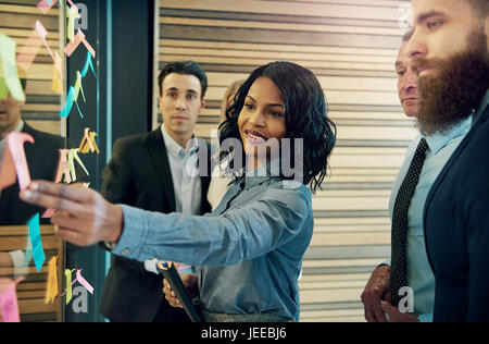 Gruppo creativo della gente di affari il brainstorming mettendo sticky notes sulla parete di vetro in office Foto Stock