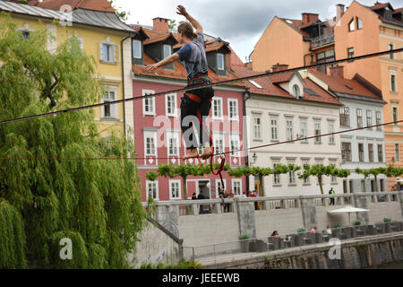 Giovane uomo in equilibrio su una linea di gioco alta oltre il fiume Ljubljanica canal nella sezione vecchia di Ljubljana Slovenia Europa Foto Stock