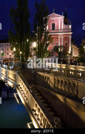 Le luci sulla facciata rosa della chiesa francescana di annunciazione e ballustrades del triplo ponte sul fiume Ljubljanica Ljubljana Slovenia Foto Stock