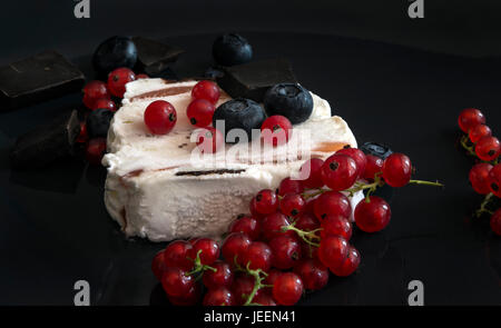 Gelato alla crema con cioccolato fondente, mirtilli e ribes rosso su sfondo nero Foto Stock