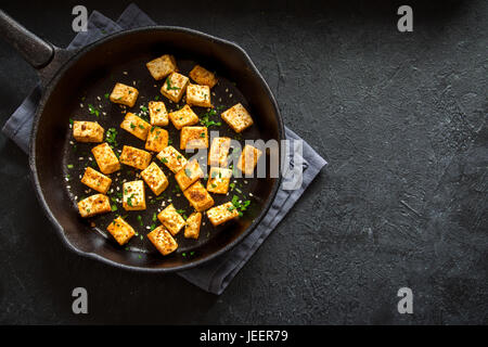 Tofu fritto con semi di sesamo e spezie su ghisa pan, copia dello spazio. Ingrediente sano per cucinare vegetariano vegano la dieta alimentare. Tofu arrosto su bla Foto Stock