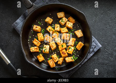 Tofu fritto con semi di sesamo e spezie su ghisa pan, copia dello spazio. Ingrediente sano per cucinare vegetariano vegano la dieta alimentare. Tofu arrosto su bla Foto Stock