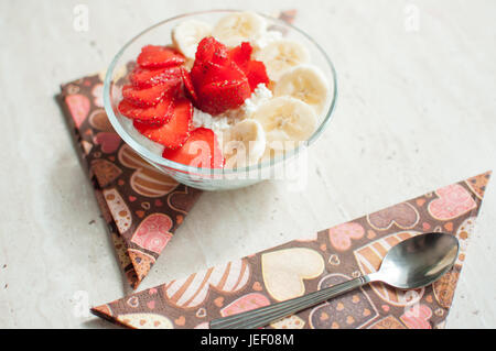 Ciotola di ricotta con fragole e banane. Close-up, il fuoco selettivo. Foto Stock