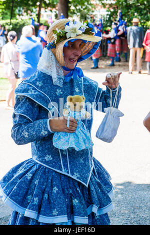 Senior lady, 60s, vestito in stile vittoriano vestito blu e del cofano della paglia, tenendo raccolta stagno e orso di peluche. Parte di Broadstairs annualmente Dickens settimana. Foto Stock
