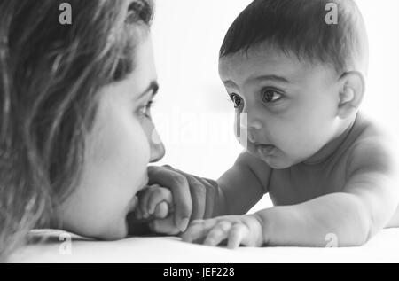 Modello rilasciato fotografia di un bambino sulla sua pancia guardando la madre contro uno sfondo bianco Foto Stock