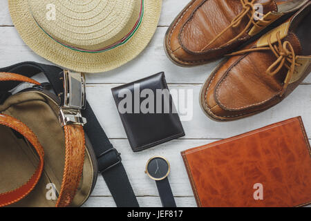 Vista superiore accessori per viaggiare con abbigliamento uomo concetto. wallet su sfondo di legno.guarda,bag,hat,notebook e la calzatura sul bianco tavola di legno. Foto Stock