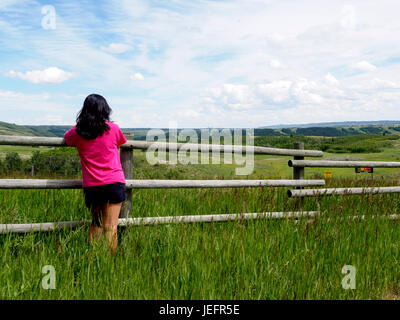 Persona che guarda oltre il recinto in legno al prairie praterie del ranch Foto Stock