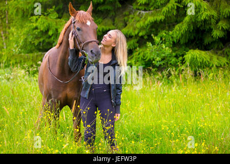 Giovane donna con il suo cavallo arabo in piedi nel campo Foto Stock