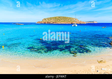 Bella sandy Cala Comte spiaggia con barca catamarano in background sul blu mare azzurro, isola di Ibiza, Spagna Foto Stock