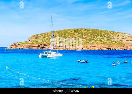 Barca catamarano sul blu azzurro mare a Cala Comte bay, isola di Ibiza, Spagna Foto Stock