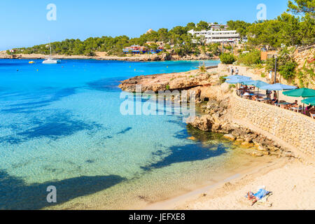 CALA PORTINATX, isola di Ibiza - Maggio 22, 2017: donna posa sulla spiaggia e la lettura di libro in Cala Portinatx bay sull isola di Ibiza, Spagna. Foto Stock