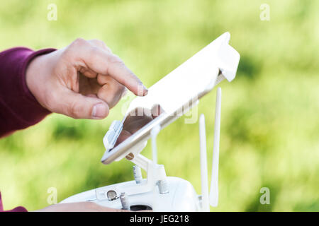 Voli quadcopter all'aperto, immagini aeree e tech hobby, concetto di ricreazione - Comodi controlli hardware per la regolazione dei parametri di fuco e fotocamera digitale, lavorare con touch screen tablet PC. Foto Stock