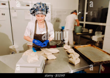 Femmina mani baker taglio pezzo di pasta con il vecchio impasto coltello raschiatore su panetteria di metallo la superficie del tavolo Foto Stock