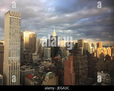 Parte di nuvole e sole splende in giù su Midtown Manhattan, grattacieli incandescente con la luce del sole. Nuvole temporalesche su New York skyline della citta'. Foto Stock