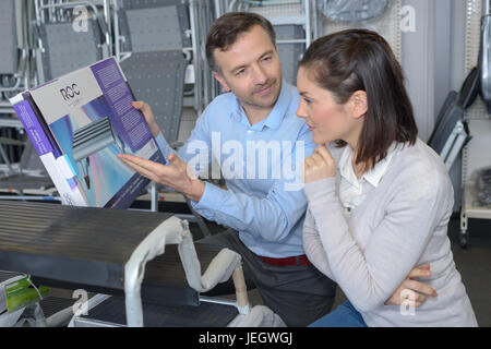 Assistente maschio venditore aiuta il cliente a scegliere la lampada in hardware Foto Stock