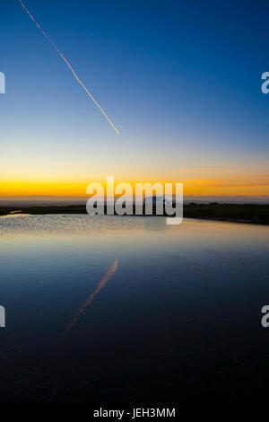 Sentiero degli aeromobili al tramonto su mori. Veicolo che viaggia attraverso mori riflessa in acqua a sun. Parco Nazionale di Dartmoor tramonto inverno, Devon, Inghilterra, Regno Unito Foto Stock