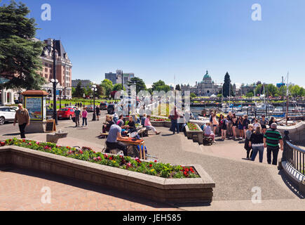 Le persone nel centro di Victoria, BC su una soleggiata giornata estiva ascoltando un batterista, musicista di strada. Wharf e strade statali. Victoria, Vancouver Islan Foto Stock