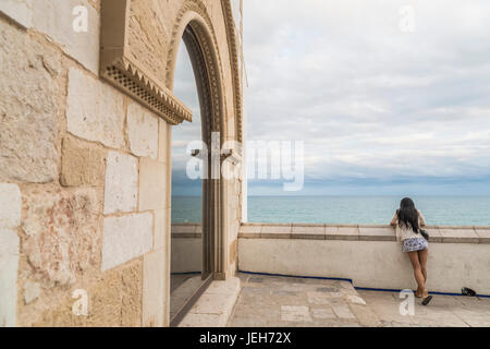 Una giovane donna si affaccia su una parete per l'oceano a Maricel Palace; Sitges, provincia di Barcellona, Spagna Foto Stock