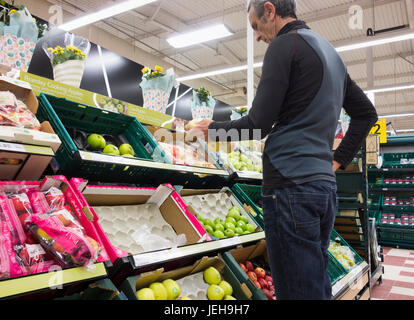 Acquirente maschio maturo che controlla il prezzo della frutta al supermercato Tesco. REGNO UNITO. Costo della vita crisi, inflazione, aumento dei prezzi dei prodotti alimentari... Foto Stock