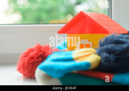 Casa giocattolo sul davanzale della finestra avvolto in una sciarpa. Il riscaldamento della casa. Foto Stock