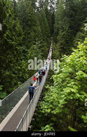 I turisti attraversando a piedi il ponte di sospensione, il Ponte Sospeso di Capilano Park; Vancouver, British Columbia, Canada Foto Stock