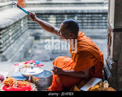 Un monaco si siede a Angkor Wat; Krong Siem Reap, Siem Reap Provincia, Cambogia Foto Stock