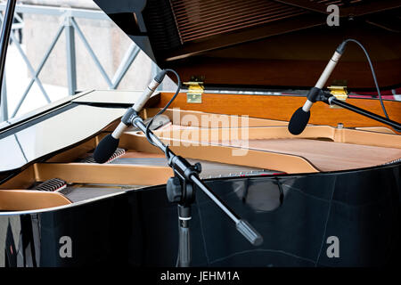 Pianoforte con coperchio rialzato. Due microfoni al di sopra delle corde di nero pianoforte. Foto Stock