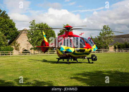 La Thames Valley Air Ambulance terre in un campo di Oxfordshire prima di trasportare un malato gravemente ferito in ospedale. Foto Stock