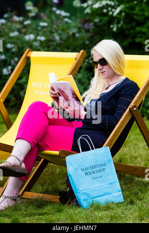 Una donna seduta in una sedia a sdraio, la lettura di un libro, al 2017 Hay Festival della letteratura e delle arti, Hay on Wye, Wales UK Foto Stock