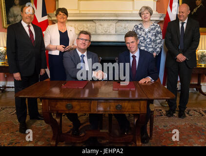 Il primo ministro Theresa Maggio stand con il primo segretario di Stato di Damian verde (a destra), DUP leader Arlene Foster (seconda a sinistra), DUP vice leader Nigel Dodds (sinistra), come DUP MP Sir Jeffrey Donaldson (terza a destra) stringe la mano con il Segretario Parlamentare al tesoro, e Chief Whip, Gavin Williamson, all'interno di 10 Downing Street, Londra, dopo la partizione DUP hanno convenuto un accordo per il supporto di una minoranza governo conservatore. Foto Stock