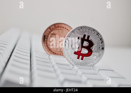 Cryptocurrency argento fisico bitcoin moneta sulla tastiera bianca in ottone vicino a Coin. Foto Stock