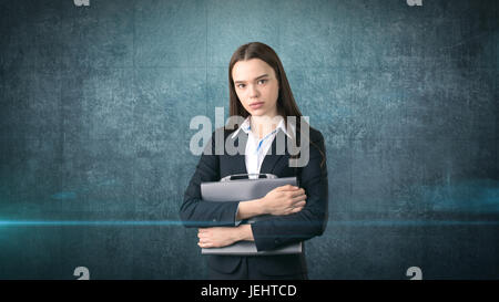 Grave giovane imprenditrice bellissimo ritratto con valigetta grigia, sfondo scuro Foto Stock