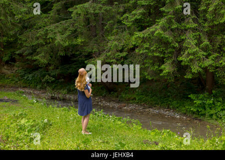 Madre tenendo la sua bimba vicino alla foresta Foto Stock