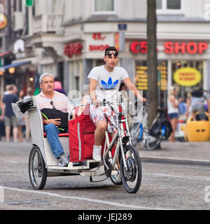 AMSTERDAM-AGO. 19, 2012. Taxi in bicicletta con passeggeri a Piazza Dam. Il taxi in bicicletta di Amsterdam offre escursioni in risciò uniche attraverso il centro della città. Foto Stock