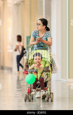 PECHINO-18 MAGGIO 2016. Donna con baby car nel centro commerciale. La Cina è molto preoccupata per l’invecchiamento della popolazione e ha posto fine alla sua politica di un figlio unico. Foto Stock